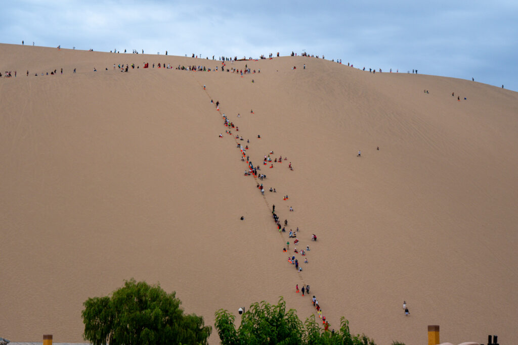 Touristen besteigen die Sanddünen